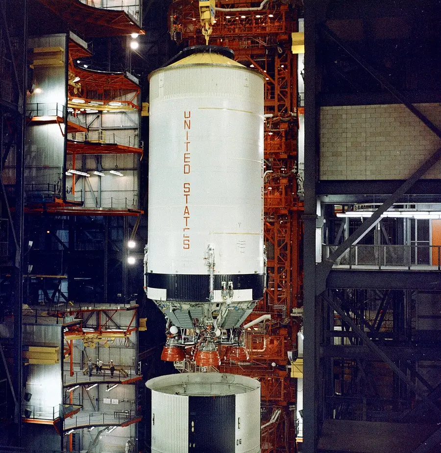 Somebody still has to stack them A Saturn V second stage, engines exposed, being lowered onto the stage below in the Vehicle Assembly Building